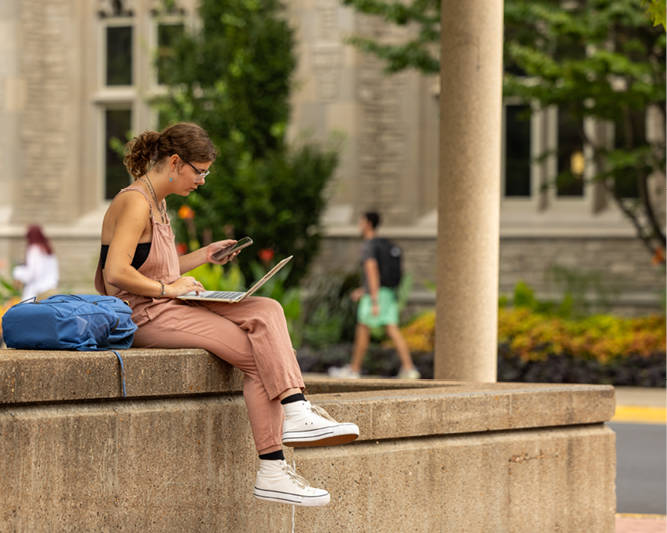 Student working on laptop on Lowry Mall.