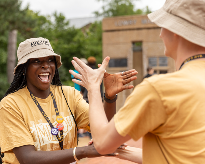 Welcome week leaders doing a handshake with one another.