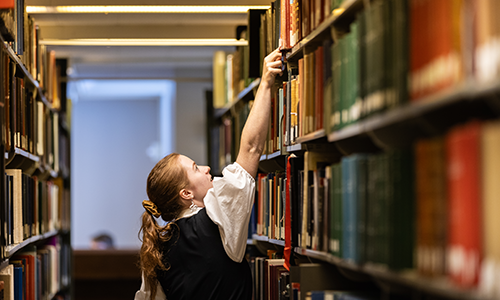 Student looking at books in library.