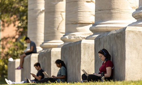 Students at columns on laptops.