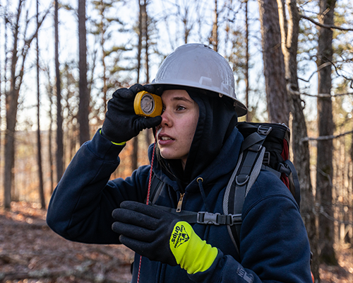 Student in the outdoors looking through outdoorsy tool.