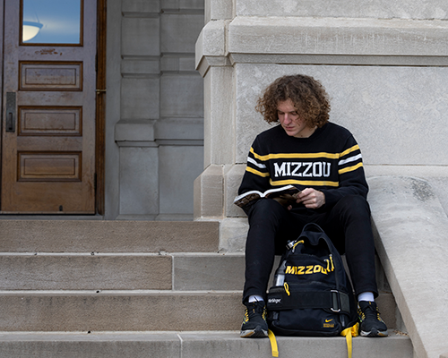 Student sitting on stairs reading.