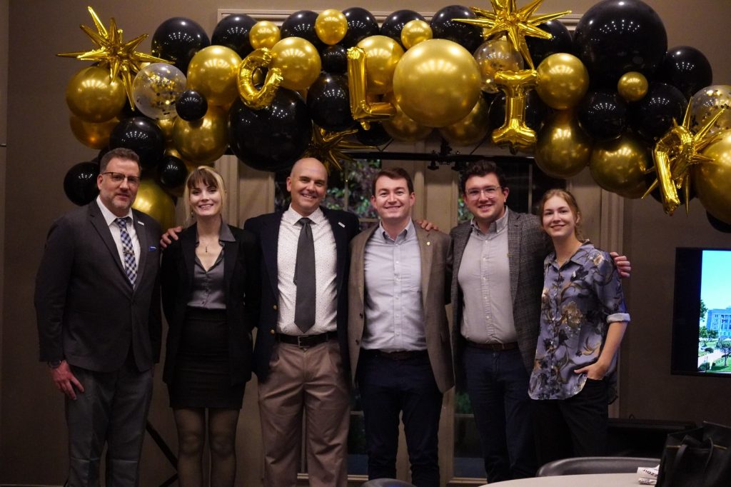 A group of coordinators for CLIP pose in front of a balloon arch at the CLIP fundraiser.