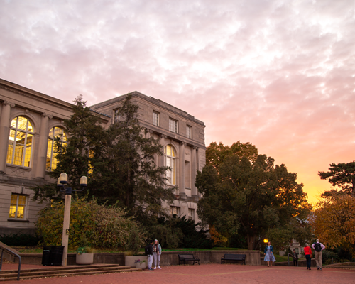 Students walking on campus during sunset.