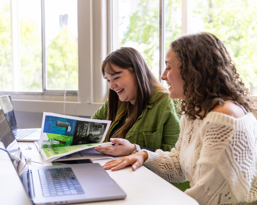 Students in front of laptop and talking.