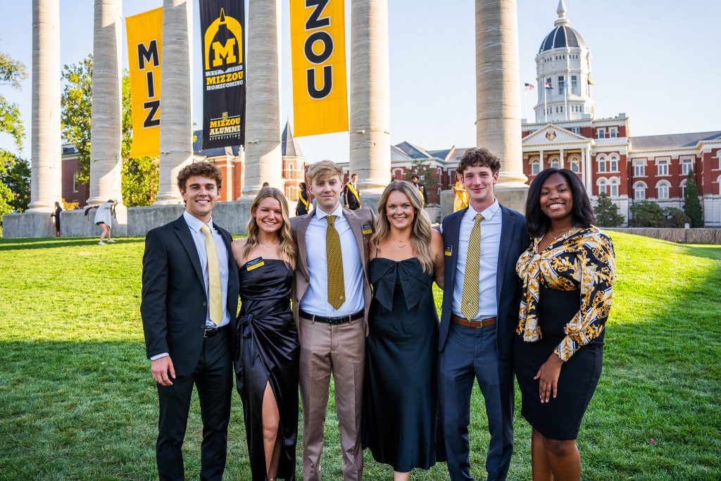 Six Mizzou students stand together smiling for a photo on the quad.