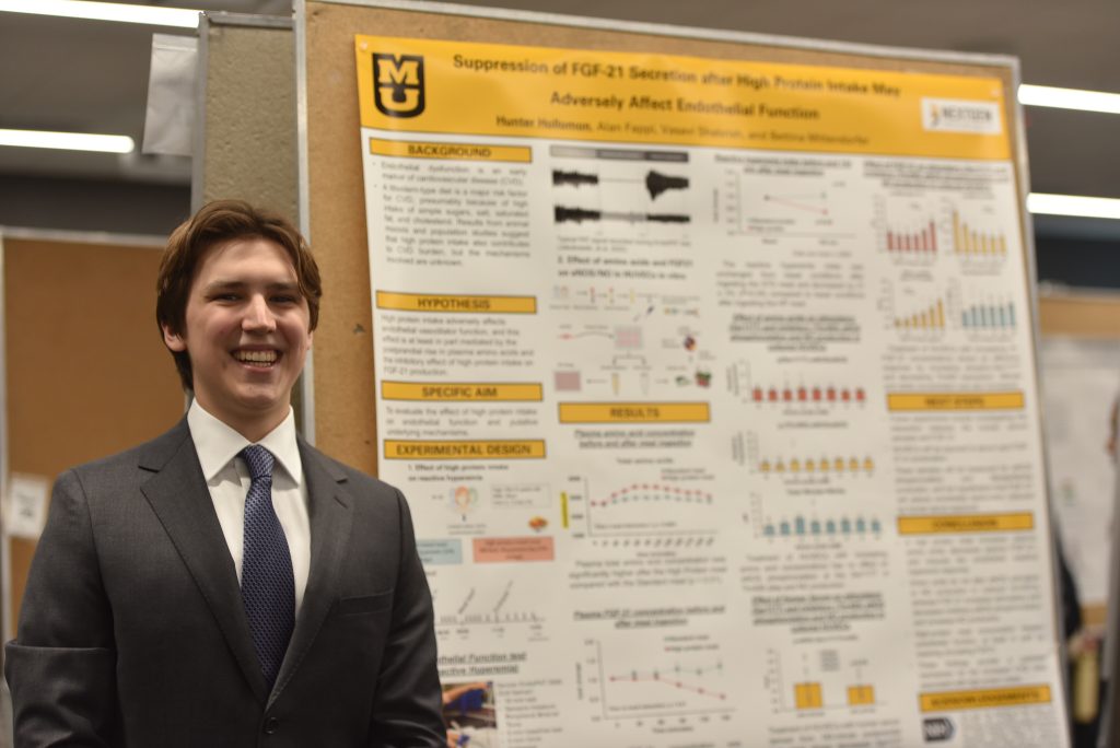 Hunter Hollomon smiles in front of his research.