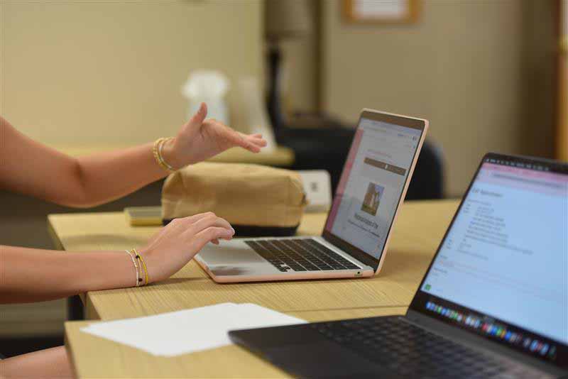 Two laptops open with a sheet of paper angles between them.