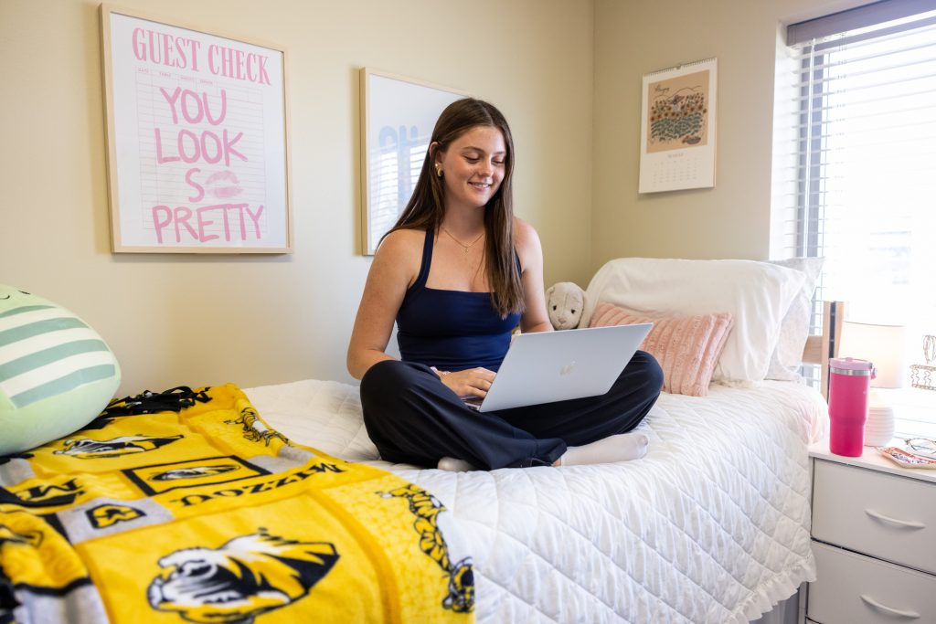Student sitting on her bed with laptop