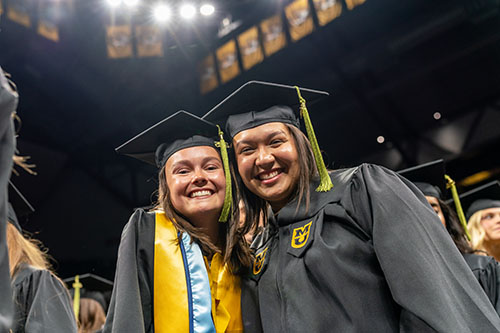 Two students posing at graduation.