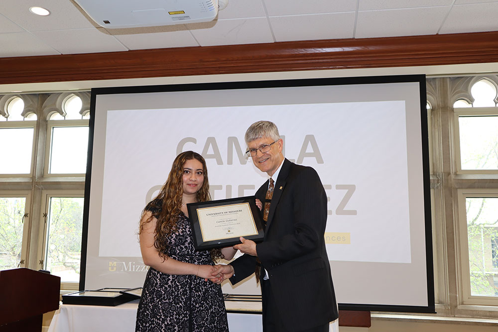 Camila Gutierrez holding certificate at awards ceremony with Dr. Spain.