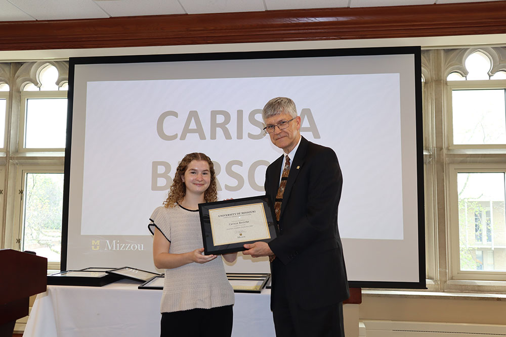 Carissa Bersche holding certificate at awards ceremony with Dr. Spain.
