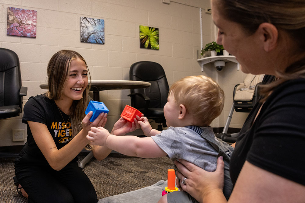 Student playing with a baby with building blocks.