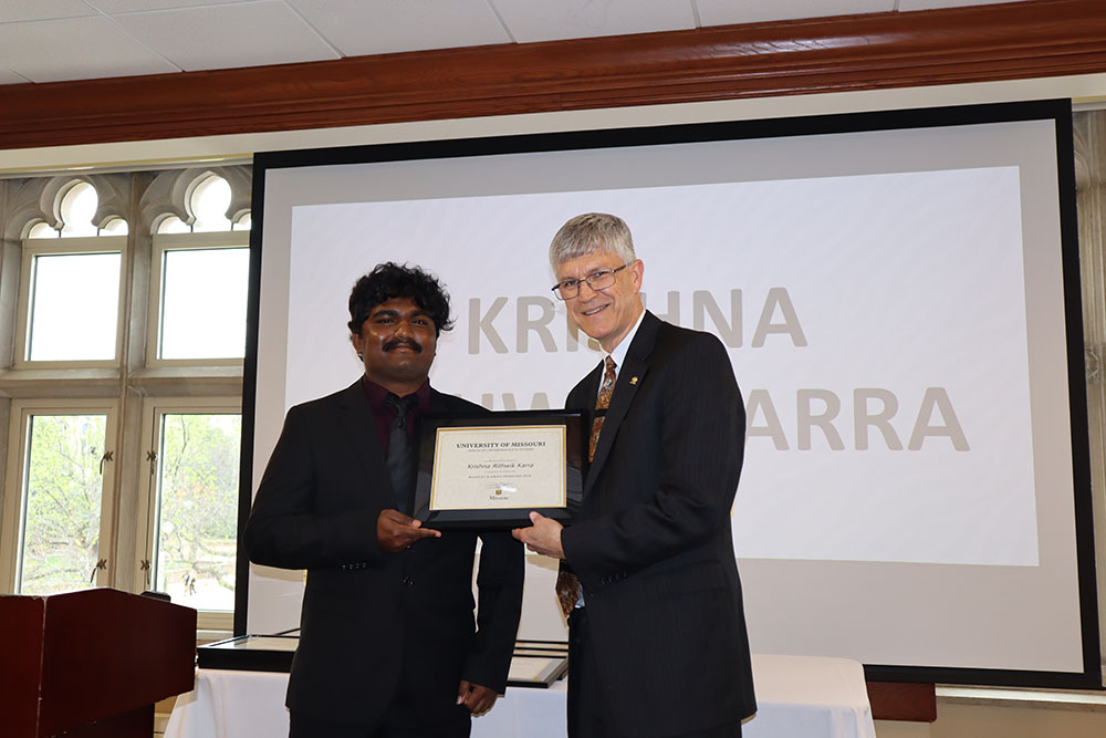 Krishna Rithwik Karra holding certificate at awards ceremony with Dr. Spain.