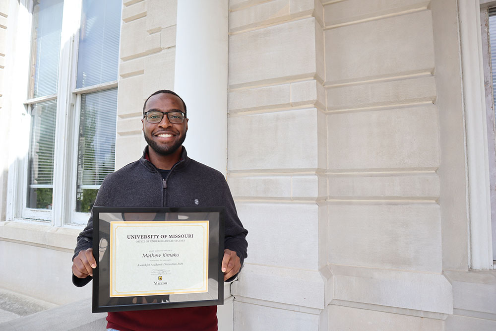 Mathew Kimaku holding certificate.