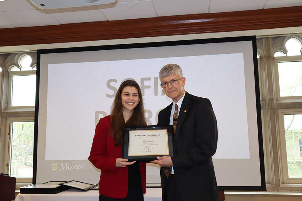 Sofia Petrov holding certificate at awards ceremony with Dr. Spain.