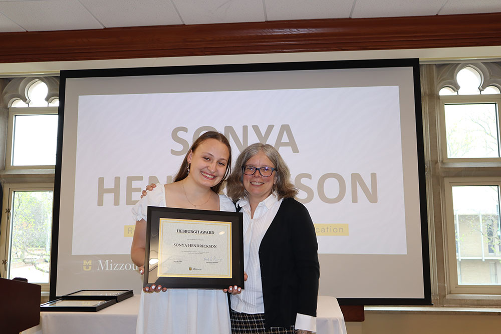 Sonya Hendrickson holding certificate at awards ceremony with Dr. Monnier.