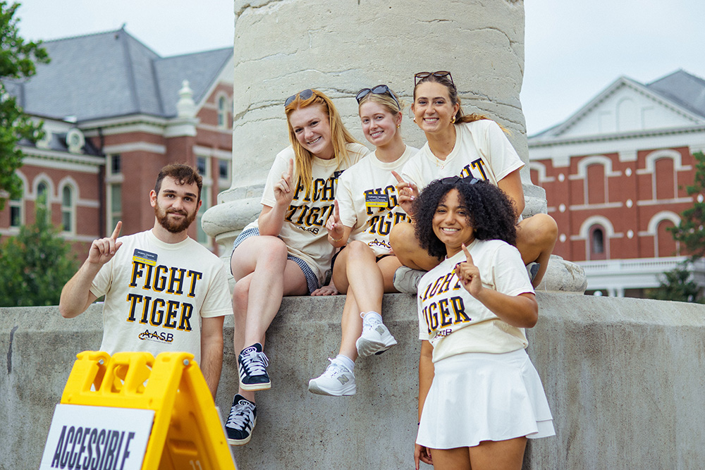 Members of Alumni Association Student Board sit on columns for First Roar.