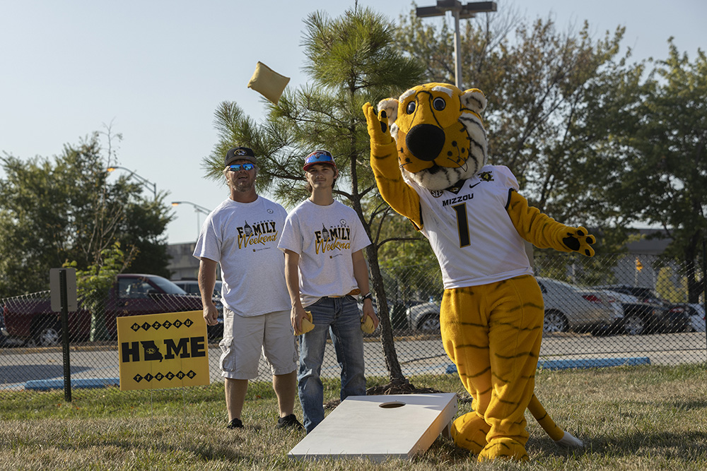 Father and son play corn hole with Truman during Family Weekend.