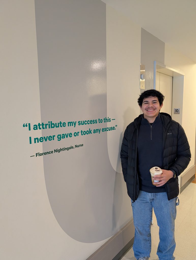 Candid photo of Ramon Torres-Gomez in front of quote on wall.